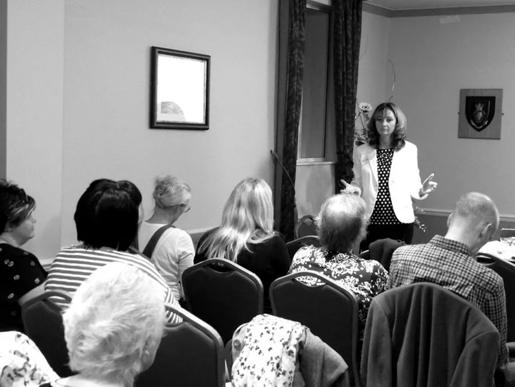 Elva Carter standing and speaking at the front of a corporate counselling event she is hosting.