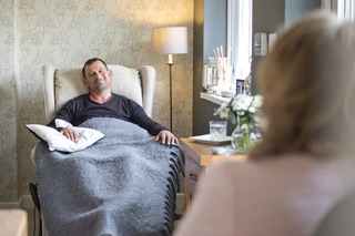 Gentleman client sat with a blanket and pillow in the therapy chair at Positive Change Therapies.