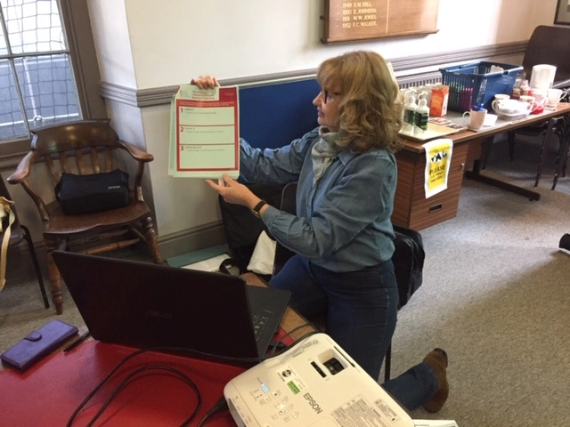 Elva Carter using two hands to hold up an A4 size self-help mental health document she created.