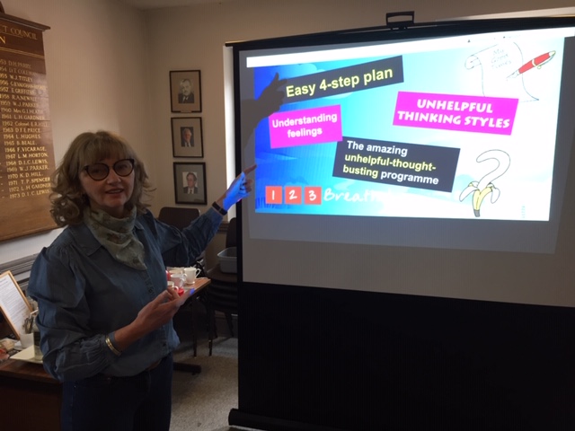 Elva Carter pointing to an interactive whiteboard displaying a slideshow she created on nurturing better mental health.
