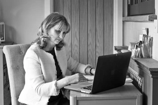 A close up of Elva Carter behind her laptop inside the Positive Change Therapies therapy room.